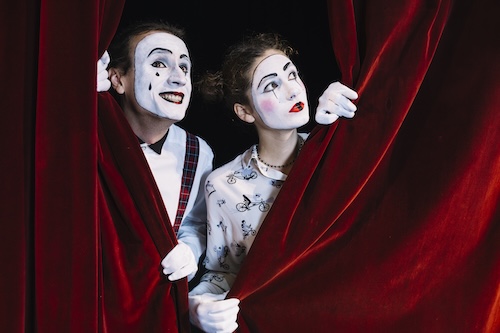 Dos actores asomándose por el telón simbolizando el inicio del segundo acto